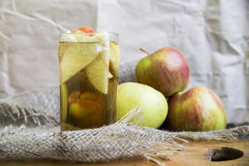 Apple cider with slices of apples in transparent glasses on a wooden board