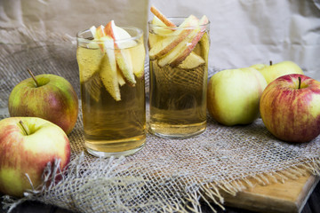 Apple cider with slices of apples in transparent glasses on a wooden board