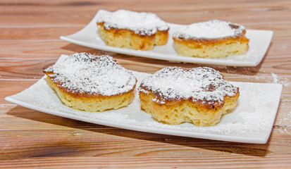 Homemade Creme brulee with powder sugar,  burnt cream, crema catalana, or Trinity cream, white plate and wood background