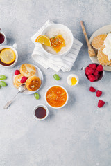 Morning atmosphere. Healthy breakfast with porridge, oatmeal, pancakes, lots of berries and snacks on blue rustic background. Copy space