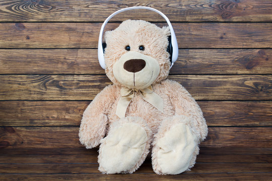 Teddy bear listens to music in white headphones