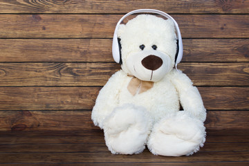 Teddy bear listens to music in white headphones