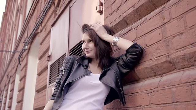 irl in a leather jacket and white t-shirt leaned against the wall of the old industrial buildings walking around the city.