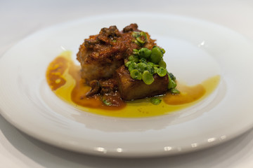 Monkfish with red sauce and broad ben in a dish.