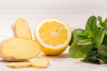 Ingredients for ginger lemonade: lemon, ginger, mint on a white wooden background. Detox water. Cleaning the body of toxins, vitamins