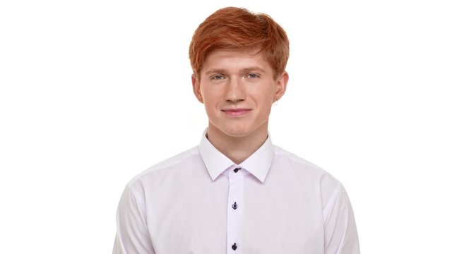 Handsome young ginger Caucasian man standing on white background and smiling