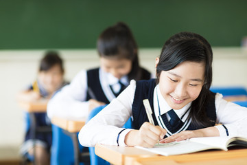 smiling student girl in classroom and her friends in background