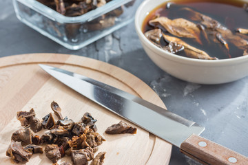 Mushroom soup cooking. Slicing mushrooms on a wooden board. Soaking mushrooms.