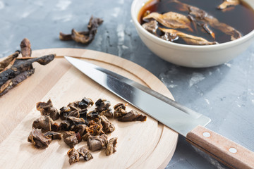 Mushroom soup cooking. Slicing mushrooms on a wooden board. Soaking mushrooms.