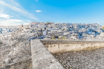 Fototapeta na wymiar panoramic view of typical stones (Sassi di Matera) near gravina of Matera UNESCO European Capital of Culture 2019 on blue sky