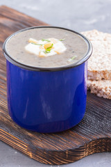 Creamy mushroom soup puree in a blue mug with crisps on wooden board. Healthy dinner. Vegetarian food. Clen and healthy eating consept.