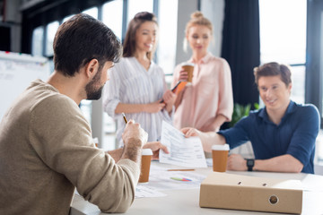 Young professional businesspeople drinking coffee while discussing and brainstorming in office