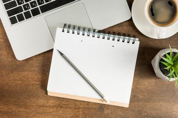 Close-up view of laptop, blank notebook and cup of coffee on wooden table top, wireless communication concept