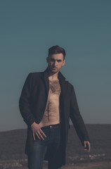 Sexy man posing in unbutton coat with naked, hairy torso