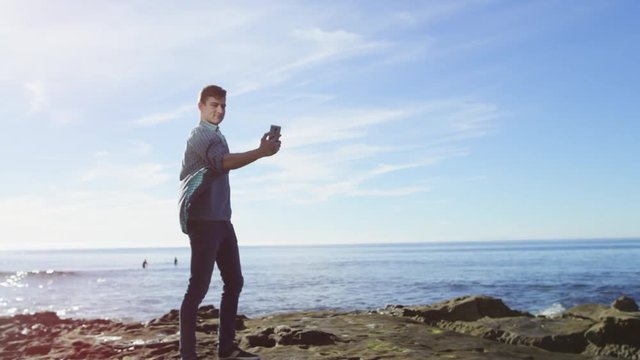Young attractive man is taking a picture of himself on a wonderful coast