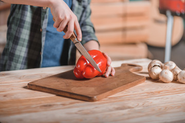 kid boy cutting bell pepper with knife on desk at backyard, cooking