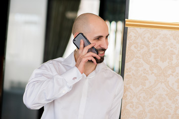 A brutal bald man talking on the phone.