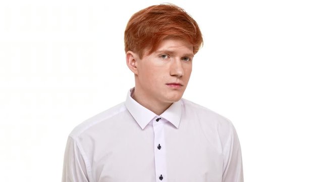 Confused young man with red hair standing on white background unsure