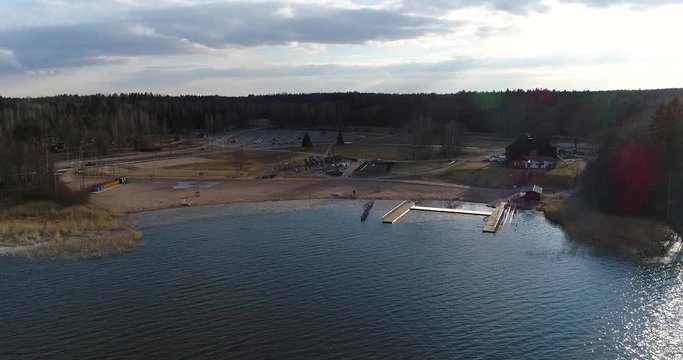 Oittaa, Cinema 4k aerial fly away view of Oittaa beach, at bodom lake, on a sunny spring day, in Espoo, Finland