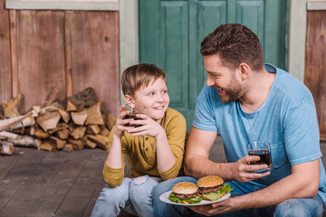 portrait of happy father and son eating homemade burgers