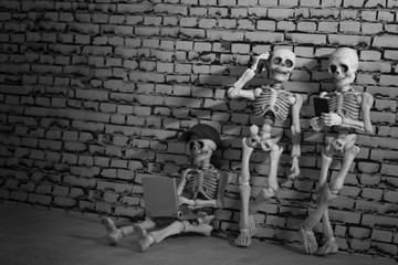 Three skeletons with smartphone and laptop 