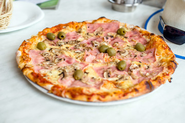 Pizza Capriciosa on white tablecloth closeup shot 