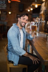 Smiling man holding beer glass at restaurant