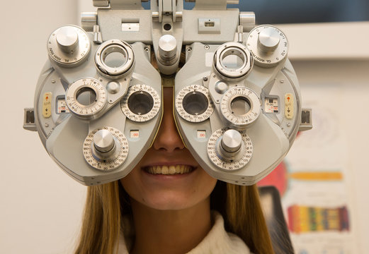 Customer in opticians shop testing eyesight in phoropter