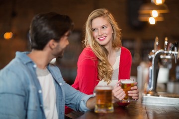 Man and woman looking at each other with holding beer glasses