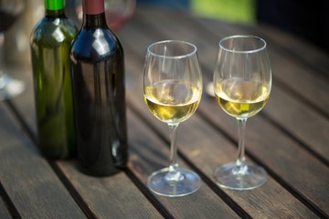 White wine in glasses by bottles on table