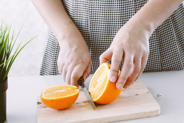 Girl cutting orange with the knife