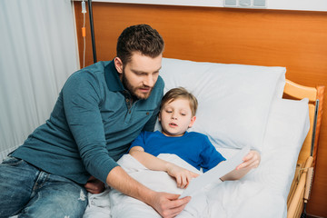 Father and son drawing together in hospital chamber, dad and son in hospital