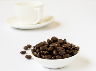 Roasted Coffee beans in a bowl with a cup