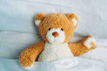 close up view of cute teddy bear toy lying in bed with drop counter