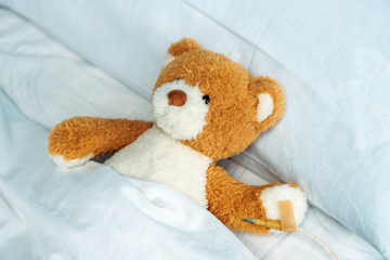 close up view of cute teddy bear toy lying in bed with drop counter
