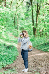 Young woman taking a photograph in the forest