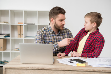 Businessman freelancer working at table with son at home office