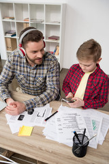 Businessman in headphones with son at office