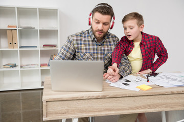 Businessman in headphones with son at office