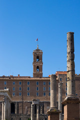 antyczna kolumna, dzwonnica i budynki w jasny słoneczny dzień