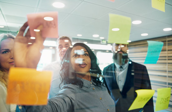 Businesswoman putting sticky note on glass