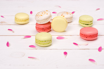 Still life of fresh macarons on the table with pink petals. sweets background concept