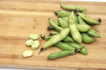 fresh broad beans on bamboo cutting board