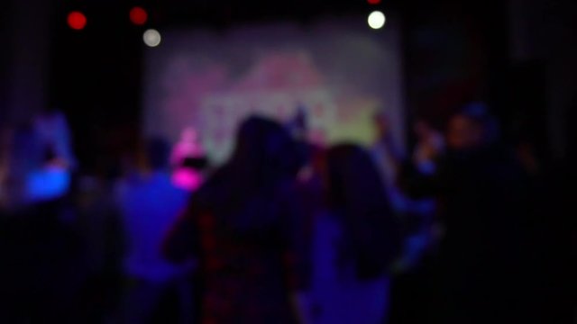 A crowd of people dancing at a rock concert in slow motion. blurred image. Out of focus.