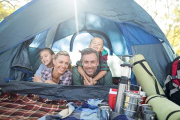 Vlies Fototapete Camping Lächelnde Familie, die im Zelt liegt