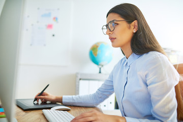 Woman working on computer with stylus and tablet