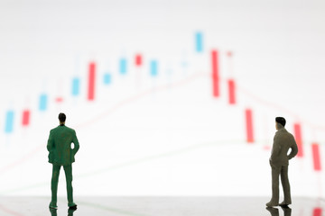 Fototapeta premium Miniature figures businessman standing on a graph chart