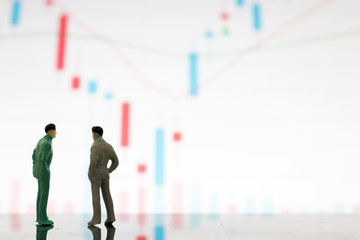 Fototapeta premium Miniature figures businessman standing on a graph chart