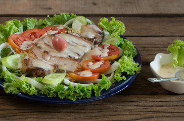 Grill pork sliced Salad on vegetable and pour with salad dressing in blue dish on old wooden table