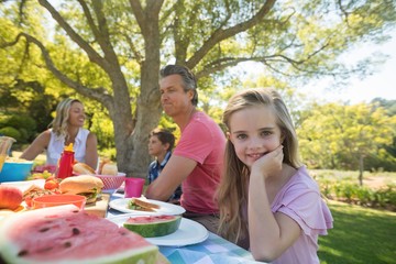 Girl sitting at the table and eating with her family 